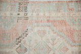 Even wear across the hand-knotted pile of a distressed Oushak rug with faded rose and ocean green colors.