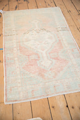 A vintage distressed Oushak rug seen from an angle, highlighting the faded color variation across the field.