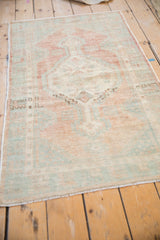 Distressed Oushak rug from an angle, highlighting the faded stepped medallion and open field design.