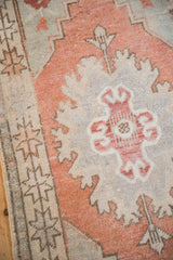 Distressed Oushak rug close up featuring pale terracotta and silver floral spandrel and geometric border.