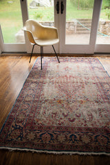 Worn ivory fringe and dark blue floral border of a vintage Kerman rug.