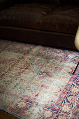 Worn vintage Kerman rug, featuring a deep blue border and faded light blue, pink, ivory floral motifs.