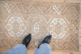 Distressed hand knotted Melas rug showcasing geometric medallion guls and pale coffee tones.