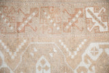Distressed texture of a vintage Turkish Melas rug featuring pale coffee and dusty copper motifs.