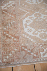 Distressed vintage Melas rug close-up, showing beige, ivory, dusty copper geometric patterns.