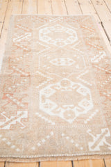Vintage distressed Melas rug pile texture, showing even wear and geometric guls in muted coffee and ivory.