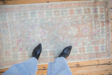 A personal perspective of a distressed Turkish Oushak rug's soft floral pattern and faded pile.