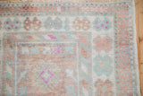 Worn pile and floral borders of a vintage Oushak rug in dusty rose, seafoam green, and ivory.