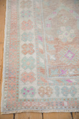 Softly worn pile on a vintage rug corner with seafoam green and dusty rose floral borders.