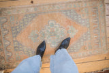Distressed vintage Oushak rug showing soft pile wear, dusty sandalwood, and slate blue floral patterns.