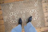 Distressed vintage Melas rug showing low pile, ivory geometric medallions and hook motifs.