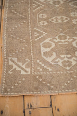 Distressed vintage Melas rug corner with ivory geometric border and intact selvage.