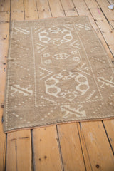 Detail of the distressed Melas rug's corner with beige tones, geometric pattern, and fringe.