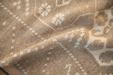 Textured pile detail of a vintage distressed Melas rug, with beige and ivory geometric patterns.
