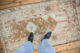 Distressed vintage Melas rug with worn texture showing prayer motif and faded ochre, bronze tones.