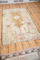 Distressed Melas rug showcasing even wear, ivory field, and arrowed blossoms within borders.