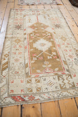 Distressed Melas rug border with geometric motifs, arrowed blossoms, and serrated leaves in faded tones.