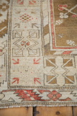 Close-up of distressed Turkish Melas rug: ivory border, red arrowed blossoms, even wear.