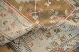 Folded Turkish Melas rug, highlighting distressed texture with ivory, ochre, and cherry red motifs.