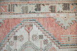 Distressed Oushak runner close-up, geometric stepped pattern in dusty blush and slate blue.