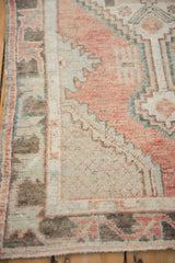 Distressed Oushak border detail with muted blush, slate blue, and charcoal floral patterns.