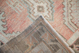 Distressed Turkish Oushak rug's faded dusty rose pile and sturdy hand-knotted foundation.