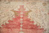 Even wear across the knot heads showing faded cherry red and ivory tones on a vintage Oushak.