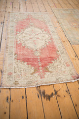 A vintage Turkish Oushak runner displaying its time-softened red and ivory palette at an angle.