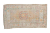 Vintage distressed Oushak rug with an octagonal medallion in dusty gold, mauve, and turquoise.