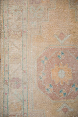 Evenly worn, hand-knotted pile of a vintage Oushak rug in dusty gold, mauve, and turquoise.