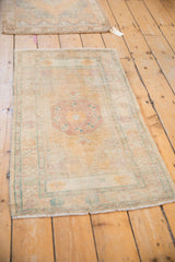 Styled view of two vintage Oushak rugs in dusty gold and mauve tones.