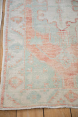 Terracotta and mint serrated leaf border of a distressed Oushak rug with worn pile.