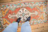 A person standing on a vintage Oushak rug runner, highlighting its scale and colorful geometric pattern.