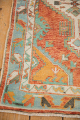 Detail of the vintage Oushak rug's floral border in rust, turquoise, and saffron yellow.