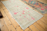 Angled view of the full distressed Oushak runner, showing its soft sea foam green and bubblegum pink tones.