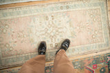 Distressed vintage Oushak runner underfoot with worn texture and soft dusty rose and blue tones.