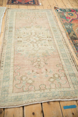 Close-up of vintage distressed Oushak rug, showing muted rose and blue-green patterns.