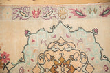 Corner detail of distressed Oushak runner: ivory, mint, blush, copper floral border with even pile wear.