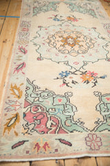 Distressed vintage Oushak rug's mint green corner spandrels and delicate floral motifs.