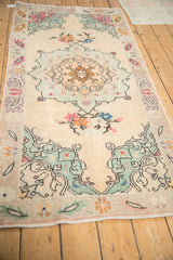 Distressed Oushak rug corner with mint green spandrel and blush serrated border.