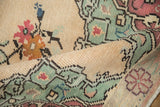 Distressed vintage Oushak rug pile with mint green serrated leaf and blush floral motifs.