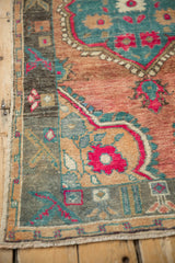 Angled view of a distressed Oushak rug corner, detailing the worn texture and floral spandrels.