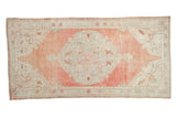 Vintage distressed Oushak rug with a large medallion in dusty cantaloupe melon and seafoam green.