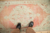 Distressed low pile of a vintage Oushak rug showing its abrashed cantaloupe field and seafoam green medallion.