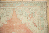 Corner detail of a distressed Oushak rug with a seafoam green palmette border and low pile.