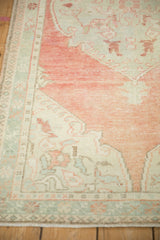 Detail of the distressed Oushak's low pile, with seafoam green and cantaloupe floral borders.