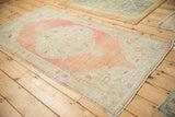 Distressed vintage Oushak rug in faded melon and seafoam, captured from an overhead angle.