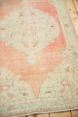 Angled view of the soft, worn texture of a distressed Oushak rug in dusty melon and seafoam.