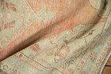Softly worn pile of a distressed Oushak rug in dusty cantaloupe and seafoam green.