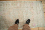 Distressed vintage Oushak rug with pale blue and melon tones, shown for scale underfoot.